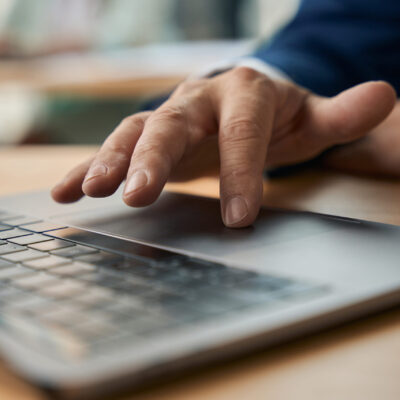 Hand tippt konzentriert auf Laptop.